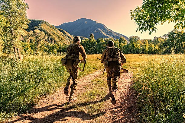 Advancing the battle, two World War II combat Soldiers take off charging across an open field.